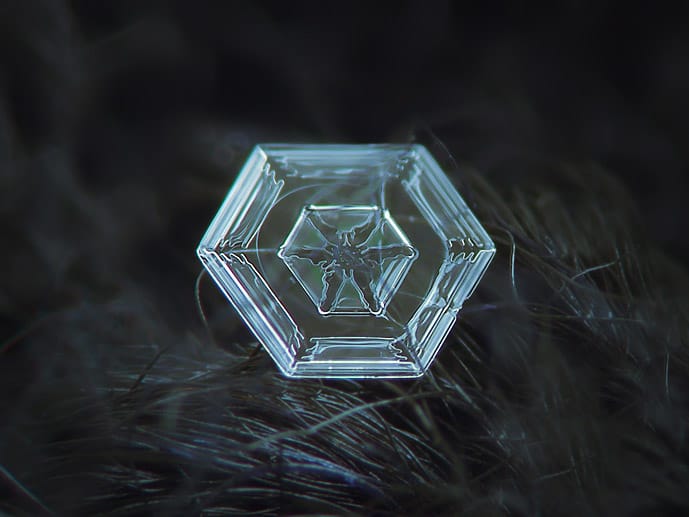 Auf dieser Aufnahme ist sehr gut die sechseckige Grundstruktur der Eiskristalle zu erkennen. Die räumliche Anordnung der Atome im Wassermolekül lässt nur ein hexagonales Kristallgitter zu.