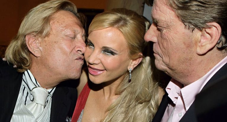 Playboy Rolf Eden küsst unter den Augen von Prinz Ferfried von Hohenzollern (r.) dessen damalige Freundin Tatjana Gsell. Die Aufnahme stammt aus dem Jahr 2006.