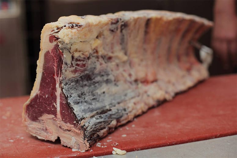Eine fast wachsartige, gelbe Schicht aus Fett umgibt das dunkelrote Fleisch mit seiner feinen Marmorierung. Dieses außergewöhnliche Steak ist intensiv aromatisch und besonders zart.