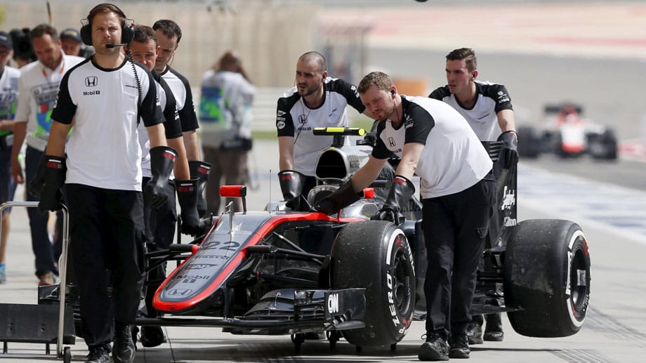 Techniker schieben den McLaren von Jenson Button zurück in die Box.