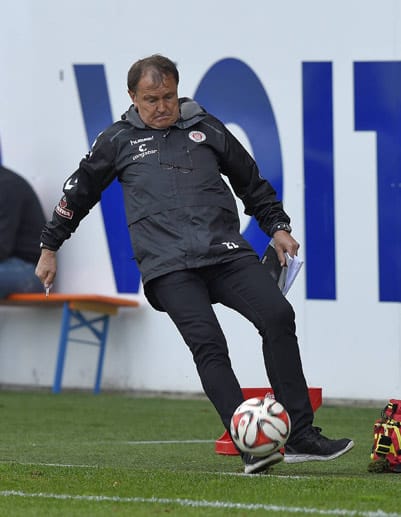 In der Partie gegen Heidenheim versucht Pauli-Coach Ewald Lienen an der Seitenlinie einen Ball zu stoppen.