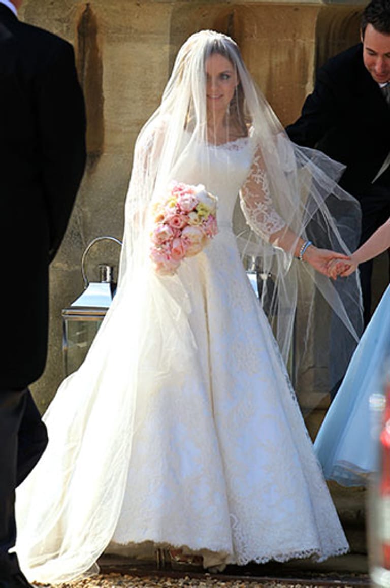 Die Braut, die ein Hochzeitskleid aus Spitze und einen dazu passenden Schleier trug, strahlte über das ganze Gesicht.