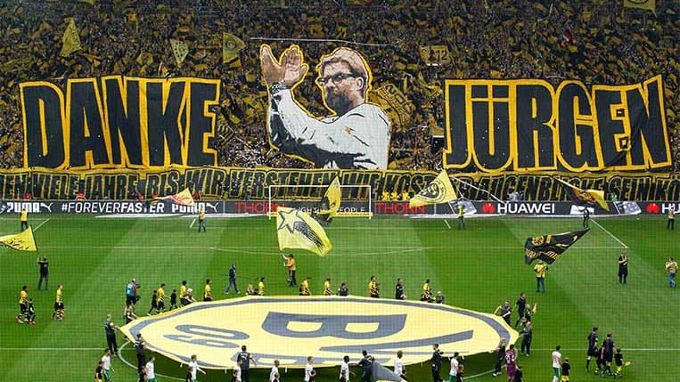 Vor dessen letztem Spiel als BVB-Trainer feiern die Fans Jürgen Klopp mit einer tollen Choreographie.