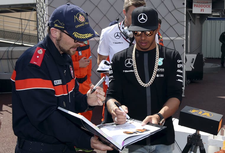 Ein Streckenmarshall holt sich ein Autogramm von Weltmeister Lewis Hamilton.
