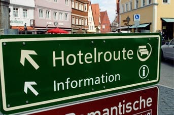 Ein Hinweisschild in Nördlingen wirbt auch in japanischer Schrift für die Romantische Straße. Sie führt von Würzburg am Main 350 Kilometer weit bis nach Füssen am Rande der Alpen. Die älteste deutsche Ferienstraße wurde nach 1950 eingerichtet um die Bedürfnisse der beginnenden Autoreisewelle zu befriedigen.