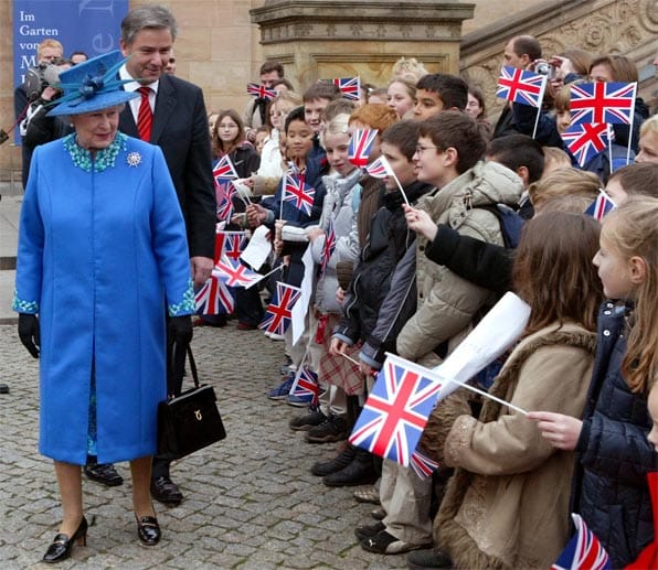 Die Queen mit Hut und Handtasche. Königsblau ist eine ihrer Lieblingsfarben. Bei ihrem dritten Staatsbesuch 2004 durfte sie der Regierende Bürgermeister, Klaus Wowereit, auf einen Spaziergang durch Berlin begleiten.