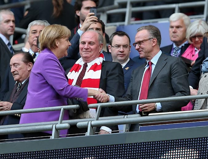 2013 holen die Bayern im Londoner Wembley-Stadion den CL-Titel gegen den großen Liga-Konkurrenten Borussia Dortmund. Der Vorstandsboss Karl-Heinz Rummenigge (re.) und der damalige Präsident Uli Hoeneß (Mitte) empfangen Kanzlerin Angela Merkel im Stadion.