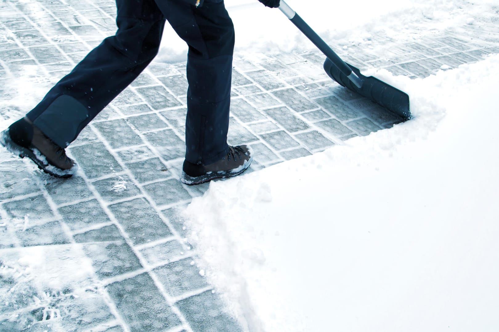 Man with shovel cleaning snow at day light