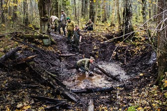 Eine Suchgruppe schöpft einen Bombenkrater ab: Die Männer legen die Spuren des Krieges frei.