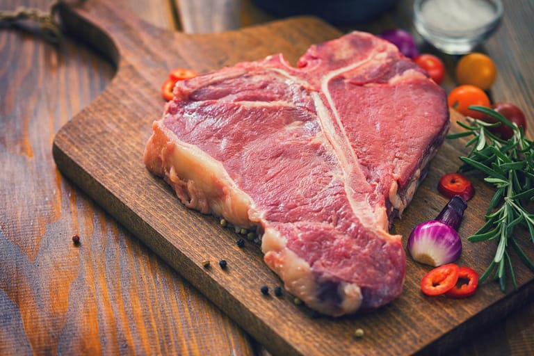 Ein rohes Steak auf einem Brett: Bei Fleisch gilt, ebenso wie bei Fisch, dass das vorgeschriebene Verbrauchsdatum unbedingt eingehalten werden sollte.