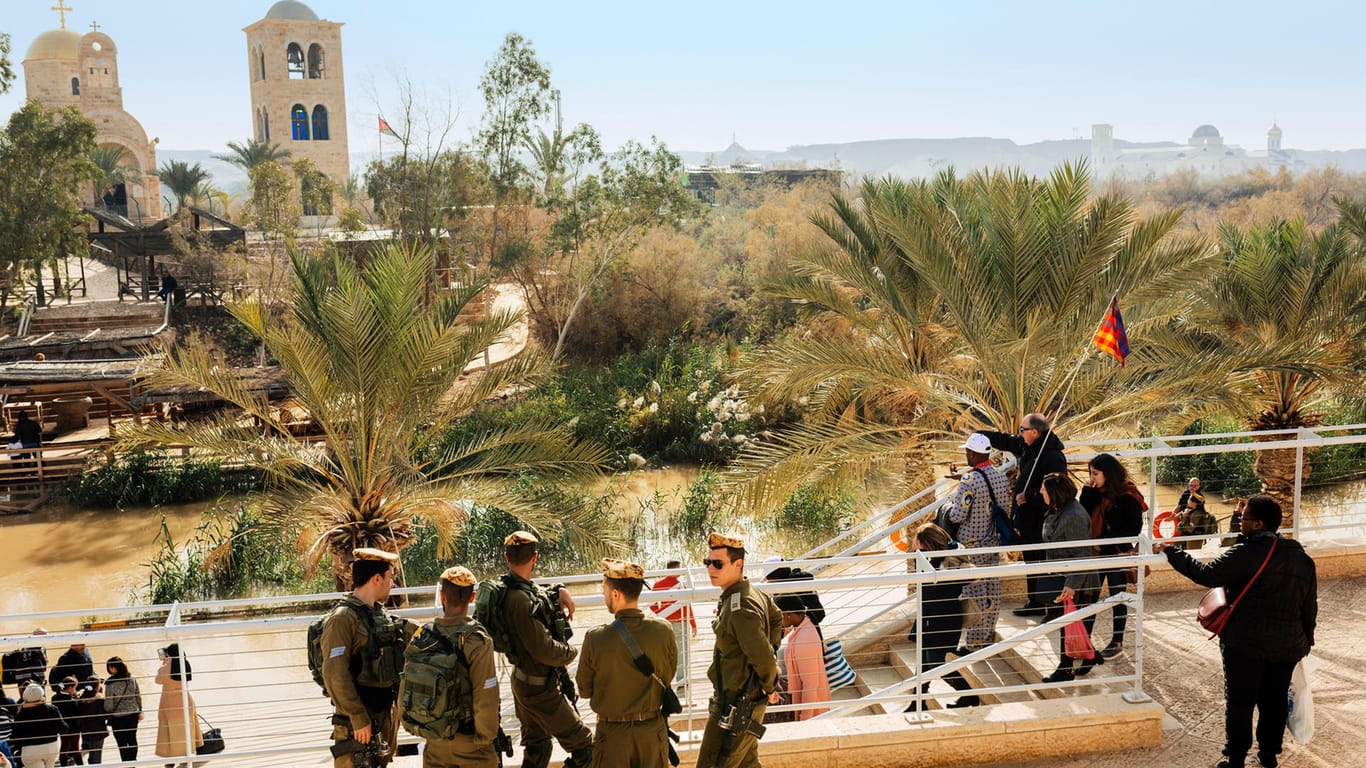 Israelische Soldaten schauen dem Treiben der Pilger zu. Auf der anderen Seite ist Jordanien. Die Grenze verläuft im Fluss.
