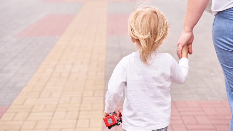 Kleines Kind an der Hand eines Erwachsenen: Menschen mit Autismus brauchen feste Tagesabläufe und Rituale.