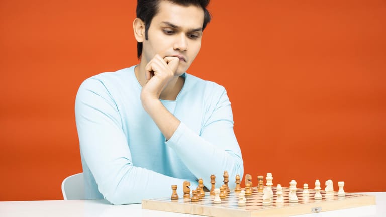 Junger Mann spielt mit sich selbst Schach: Menschen mit Asperger-Autismus fallen häufig durch besondere Fähigkeiten auf einem Spezialgebiet auf.