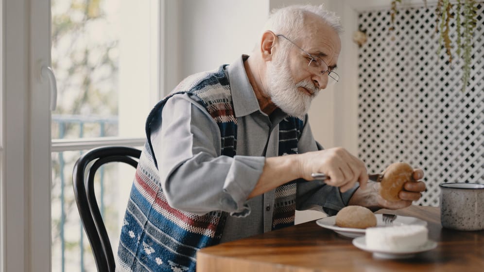 Älterer Mann frühstückt alleine (Symbolbild): Auf die Witwenrente wird das eigene Einkommen angerechnet