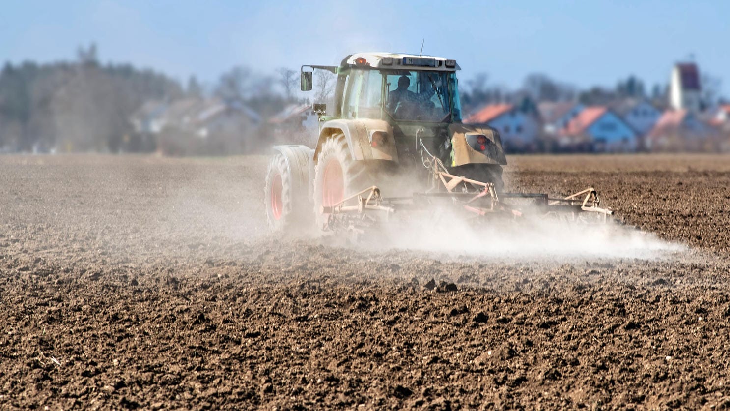 Bei der Fahrt dieses Traktors über einen Acker bei München staubt es stark: Nach einem sehr niederschlagsarmen März sind die Böden an der Oberfläche extrem trocken. In den tieferen Schichten ist noch Wasser aus den Wintermonaten gespeichert.