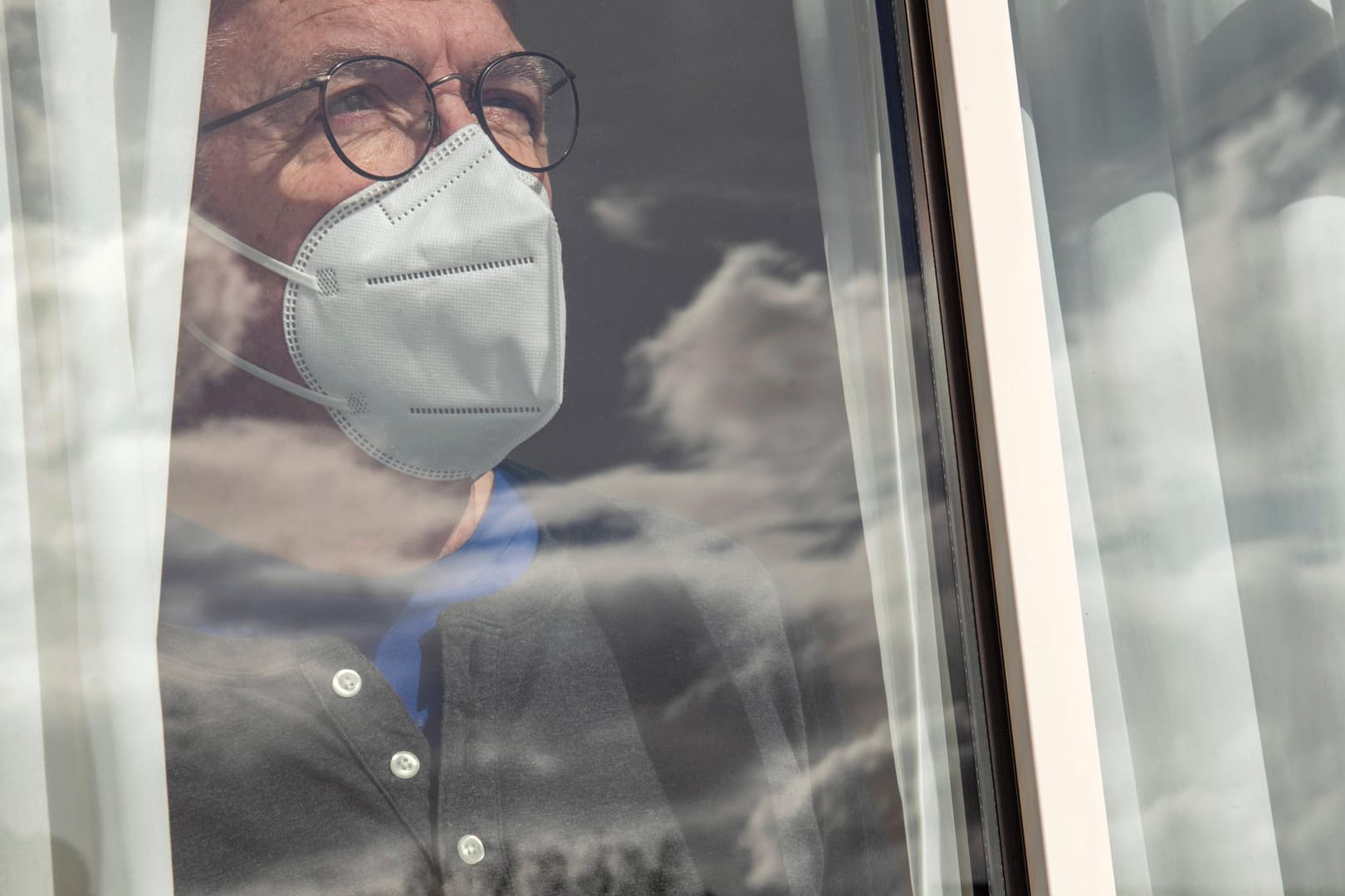 Ein Corona-Patient steht am Fenster (Symbolbild): Langsam sinkt die Inzidenz wieder