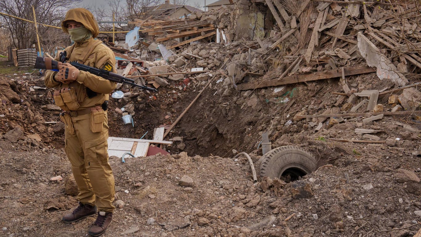 Ein ukrainischer Soldat steht an der Straße nach Cherson, wo Häuser durch russische Angriffe zerstört wurden.