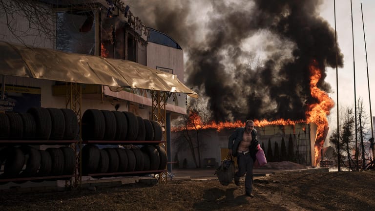 Ein Mann flieht aus einem brennenden Geschäft in Charkiw: Während Russland angeblich einen "Rückzug" plant, beschießt es weiter Zivilisten.