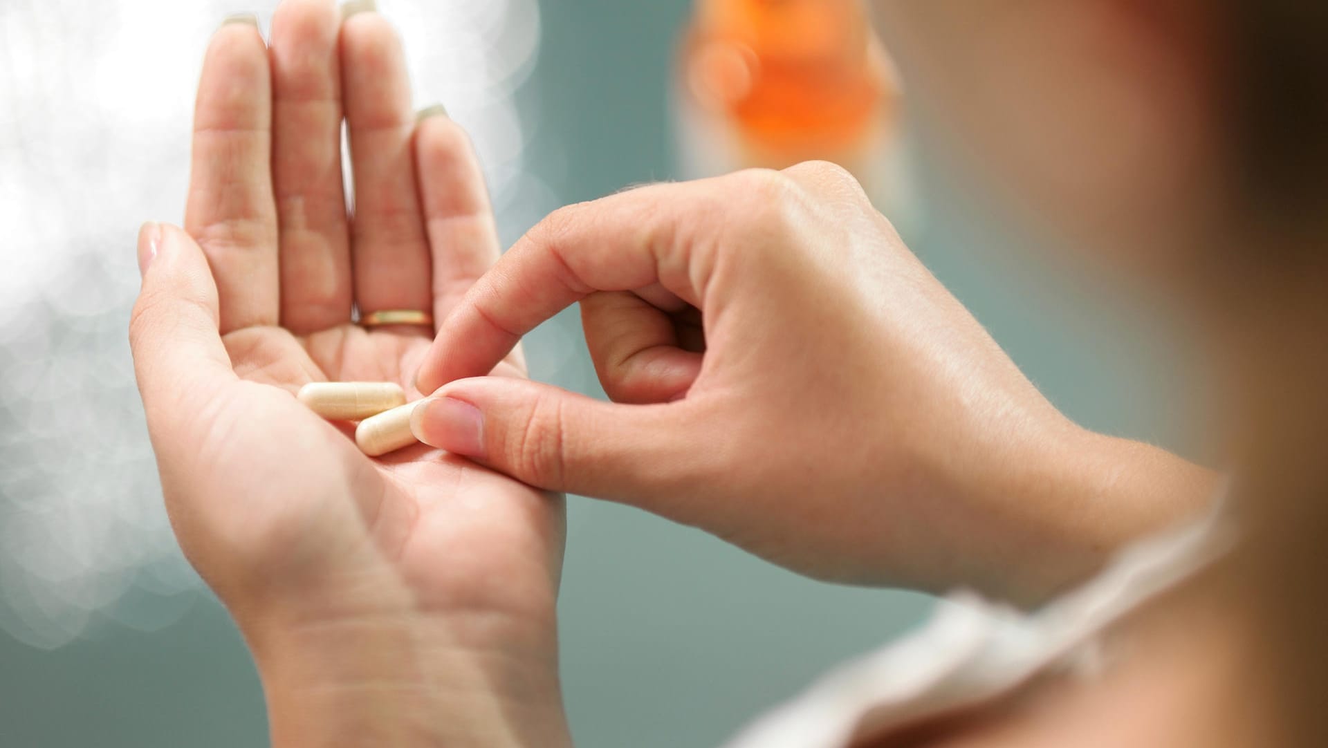 Eine Frau mit Kapseln in der Hand. Kalziumtabletten sollten nicht leichtfertig und ohne Absprache mit dem Arzt eingenommen werden.