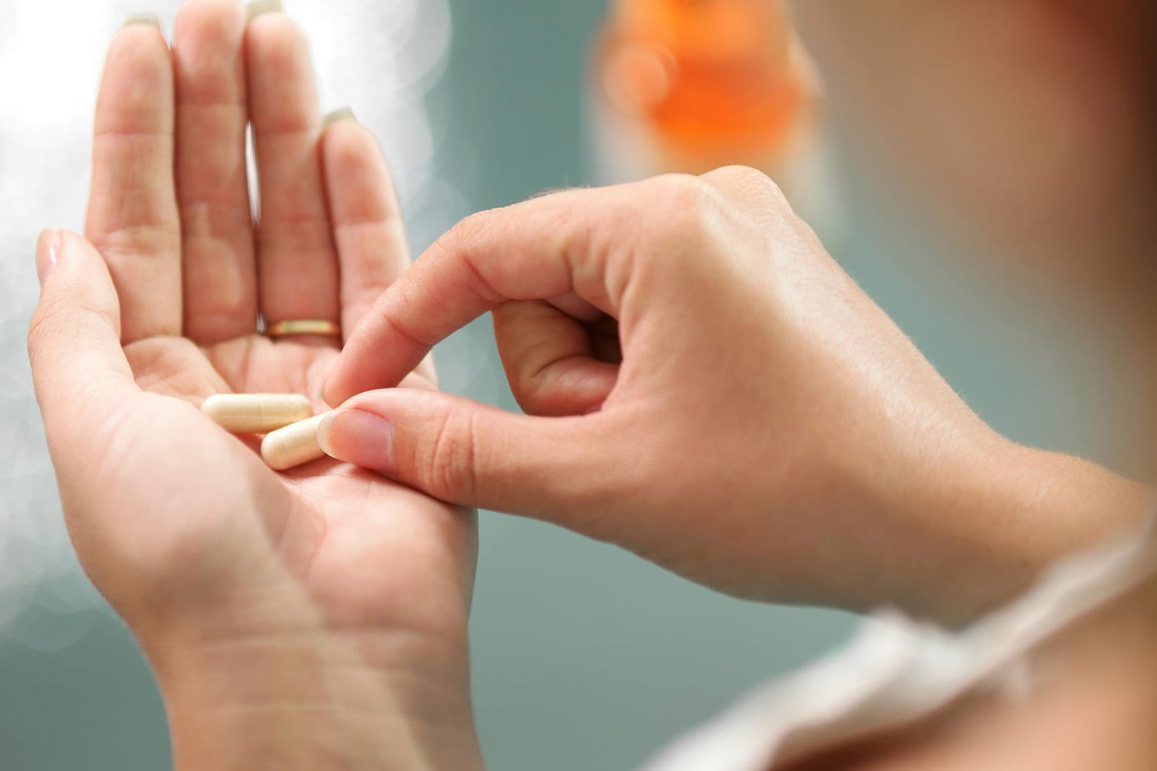 Eine Frau mit Kapseln in der Hand. Kalziumtabletten sollten nicht leichtfertig und ohne Absprache mit dem Arzt eingenommen werden.