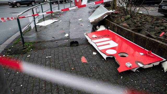 Ein zerstörtes Schild mit dem Logo der Sparkasse liegt auf dem Boden nahe eines gesprengten Geldautomaten.