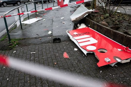 Ein zerstörtes Schild mit dem Logo der Sparkasse liegt auf dem Boden nahe eines gesprengten Geldautomaten.