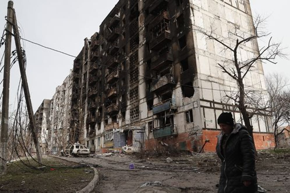 Eine Frau geht an einem beschädigten Gebäude in Mariupol vorbei.