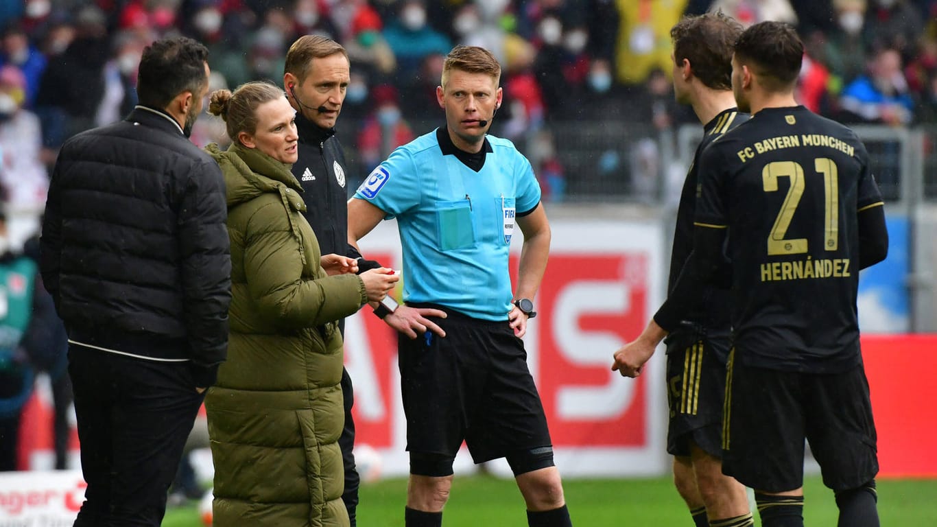 Das Schiedsrichter-Gespann um Christian Dingert (m.) diskutiert mit den Bayern-Vertretern um Teammanagerin Kathleen Krüger.