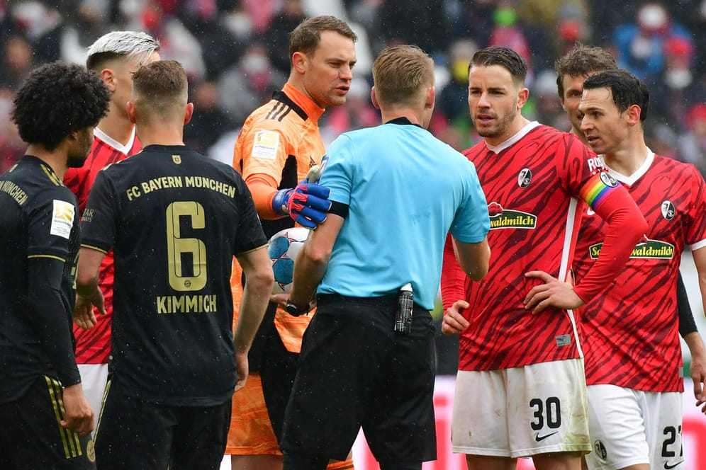 Schiedsrichter Christian Dingert diskutiert mit den Kapitänen: Die Partie in Freiburg hatte eine turbulente Schlussphase.