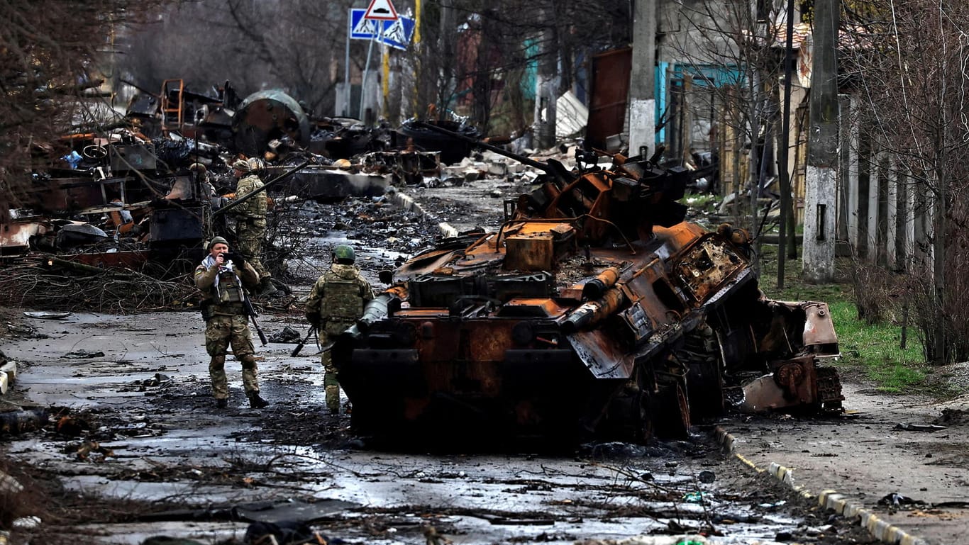Ukrainische Soldaten zwischen zerstörten russischen Panzern in Butscha: In dem Kiewer Vorort haben russische Truppen Kriegsverbrechen verübt.