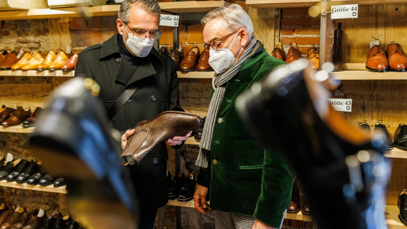 Zwei Männer tragen in einem Schuhgeschäft Maske (Symbolbild): Der Schutz ist jetzt in den meisten Gebieten Deutschlands freiwillig.