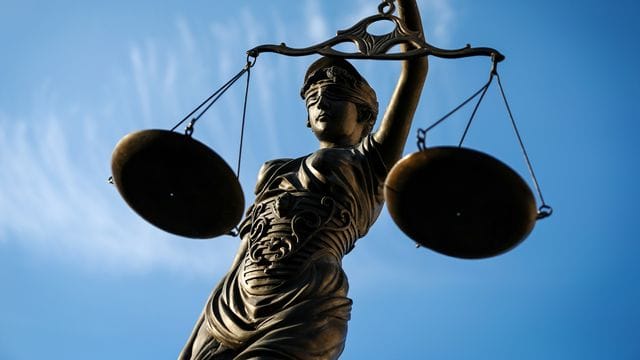 Eine Bronzefigur der Justitia hält eine Waage in der Hand