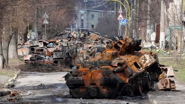 Ukrainische Soldaten untersuchen zerstörte russische Militärfahrzeuge in Butscha.