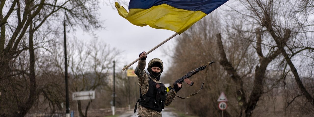 Ein ukrainischer Soldat schwenkt die ukrainische Flagge auf einer Straße in Butscha.