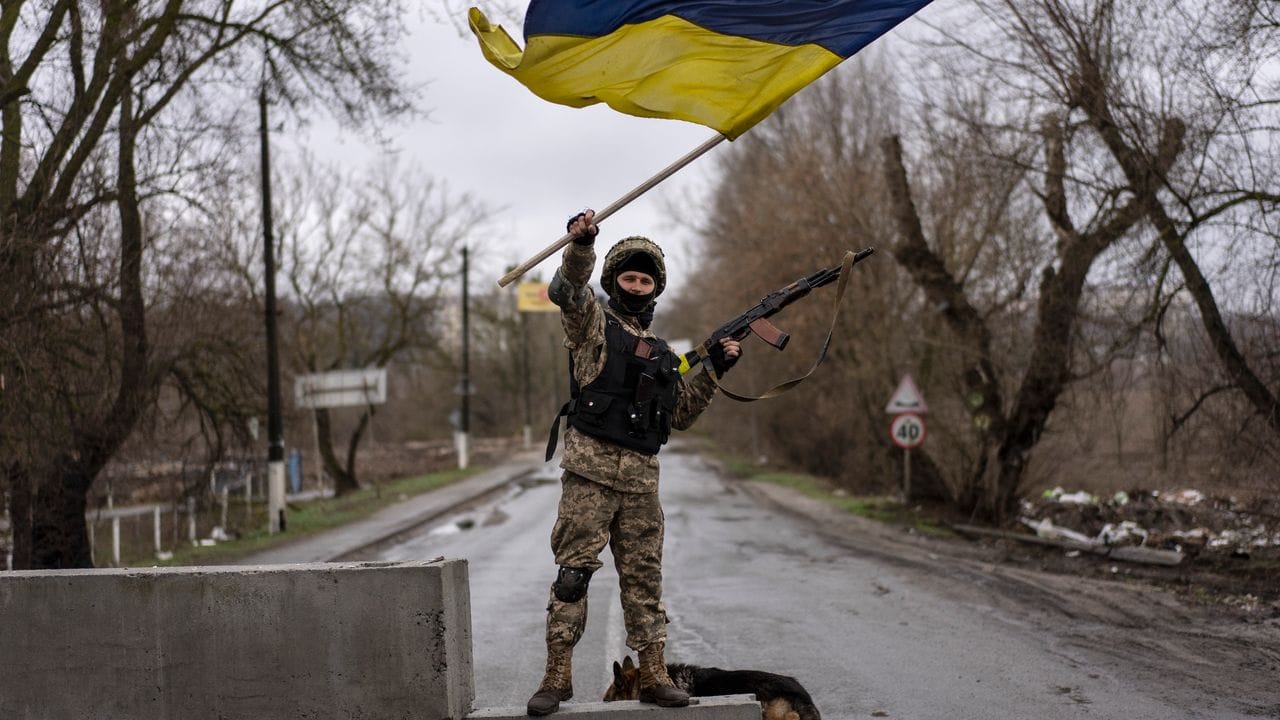 Ein ukrainischer Soldat schwenkt die ukrainische Flagge auf einer Straße in Butscha.