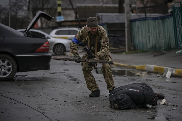 Ein ukrainischer Soldat untersucht den leblosen Körper eines Zivilisten auf Sprengfallen. Der ukrainische Präsident Selenskyj warnte, dass die sich zurückziehenden russischen Truppen Minen, Ausrüstung und sogar die Leichen der Getöteten zurücklassen.