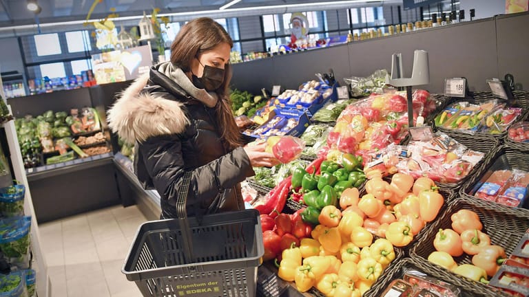 Frau vergleicht Preise an der Gemüsetheke im Supermarkt (Symbolfoto): Lebensmittel werden teurer. Münchner Jusos wollen Supermarkt-Unternehmen enteignen.