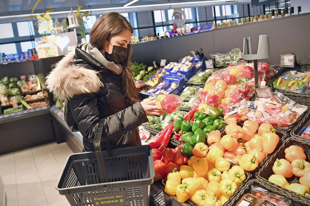 Frau vergleicht Preise an der Gemüsetheke im Supermarkt (Symbolfoto): Lebensmittel werden teurer. Münchner Jusos wollen Supermarkt-Unternehmen enteignen.