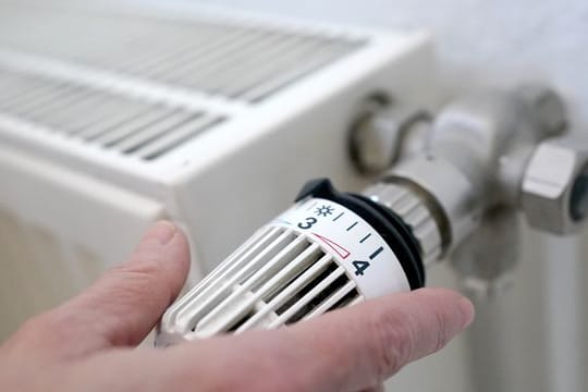 Eine Frau dreht an einem Heizungsthermostat.