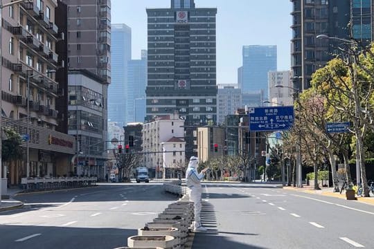 Ein Mann in einem Schutzanzug steht inmitten leerer Straßen in einem abgesperrten Gebiet im Bezirk Jingan im Westen von Shanghai.