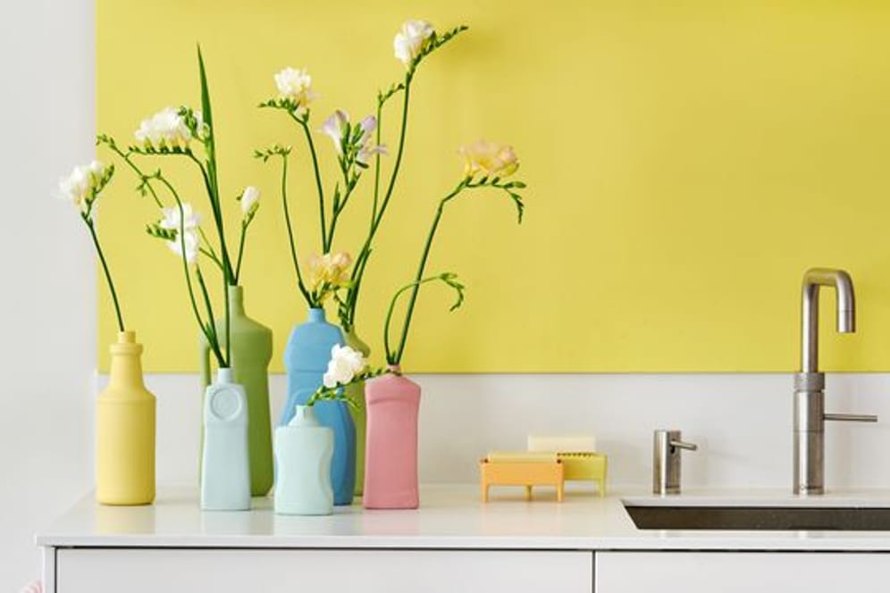 Matte Pastellfarben machen alte Plastikflaschen zu ausgefallenen Vasen für einzelne Blumen.