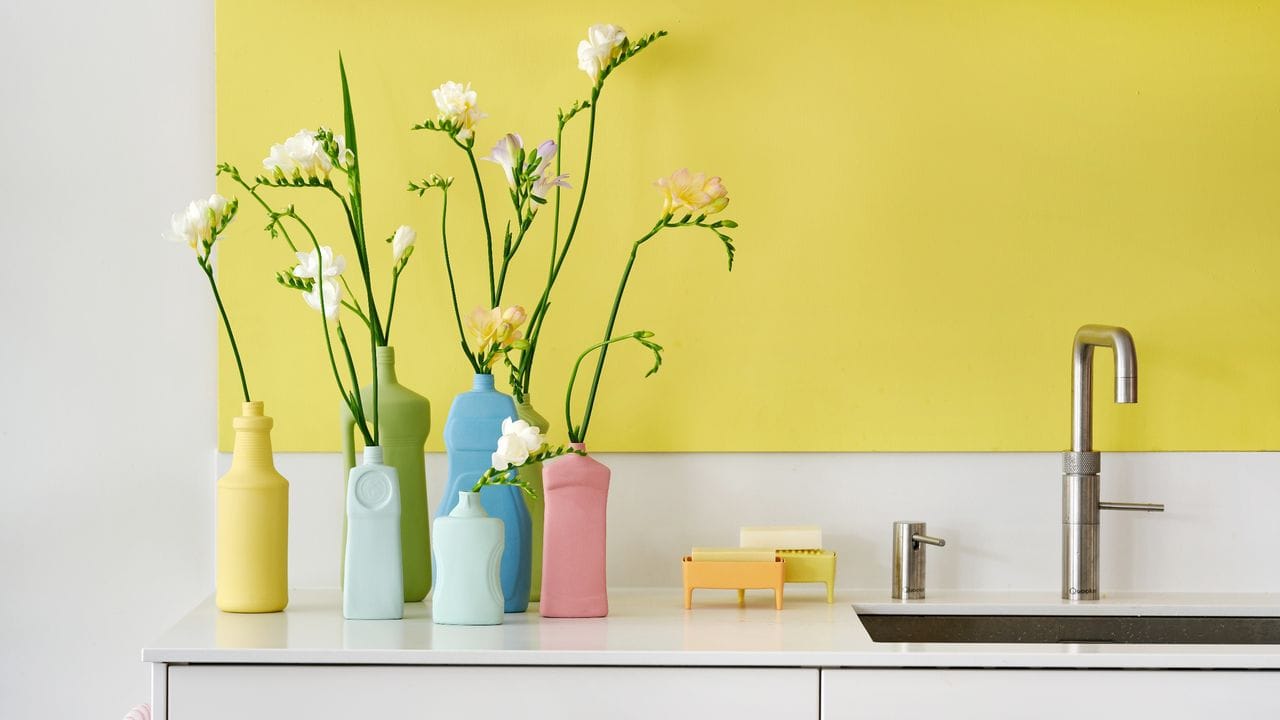 Matte Pastellfarben machen alte Plastikflaschen zu ausgefallenen Vasen für einzelne Blumen.