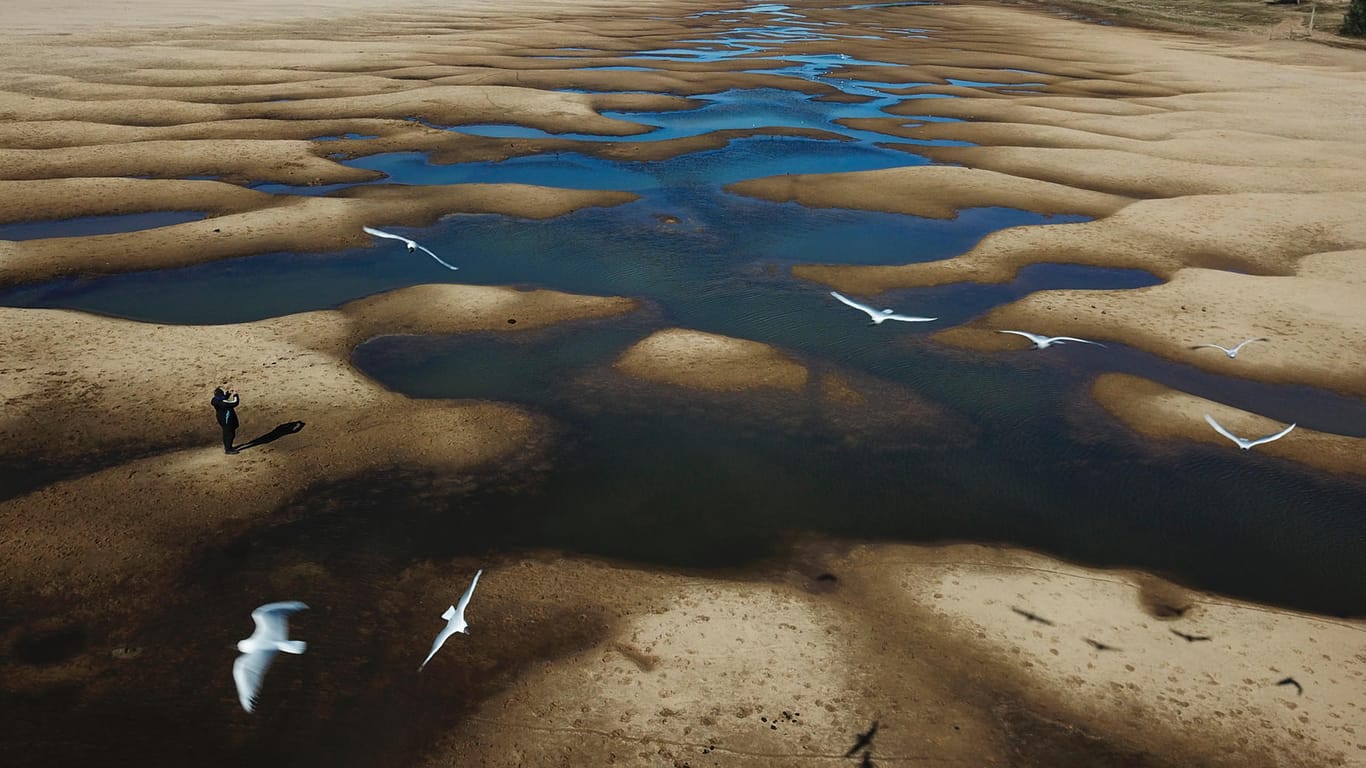 Ein Mann fotografiert das nahezu ausgetrocknete Flussbett des Parana in Argentinien: Der Fluss ist nicht nur Wasserweg, sondern auch Trinkwasserquelle für 40 Millionen Menschen in Südamerika. Mit dem Fortschreiten der Klimakrise sinkt der Pegel.
