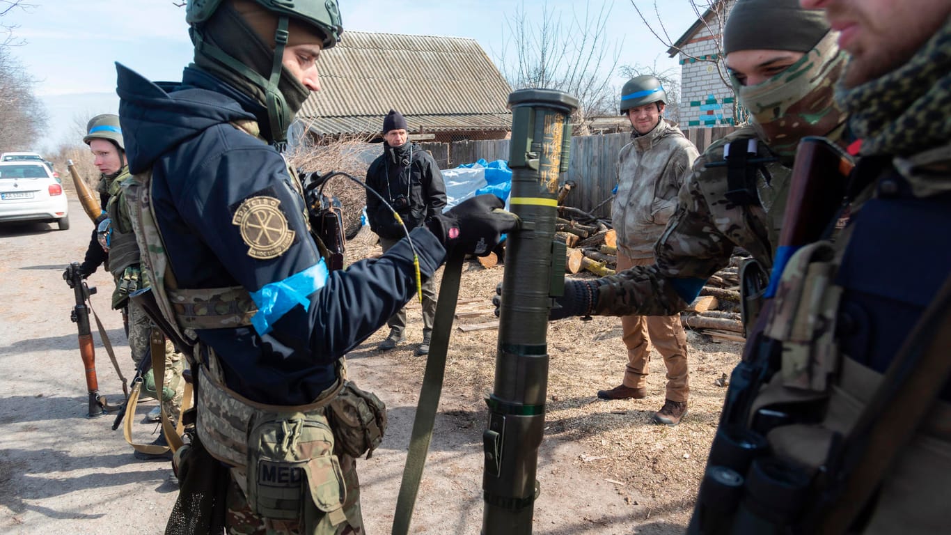 Zwei Ukrainische Soldaten halten eine Panzerfaust, während weitere die Szene beobachten.
