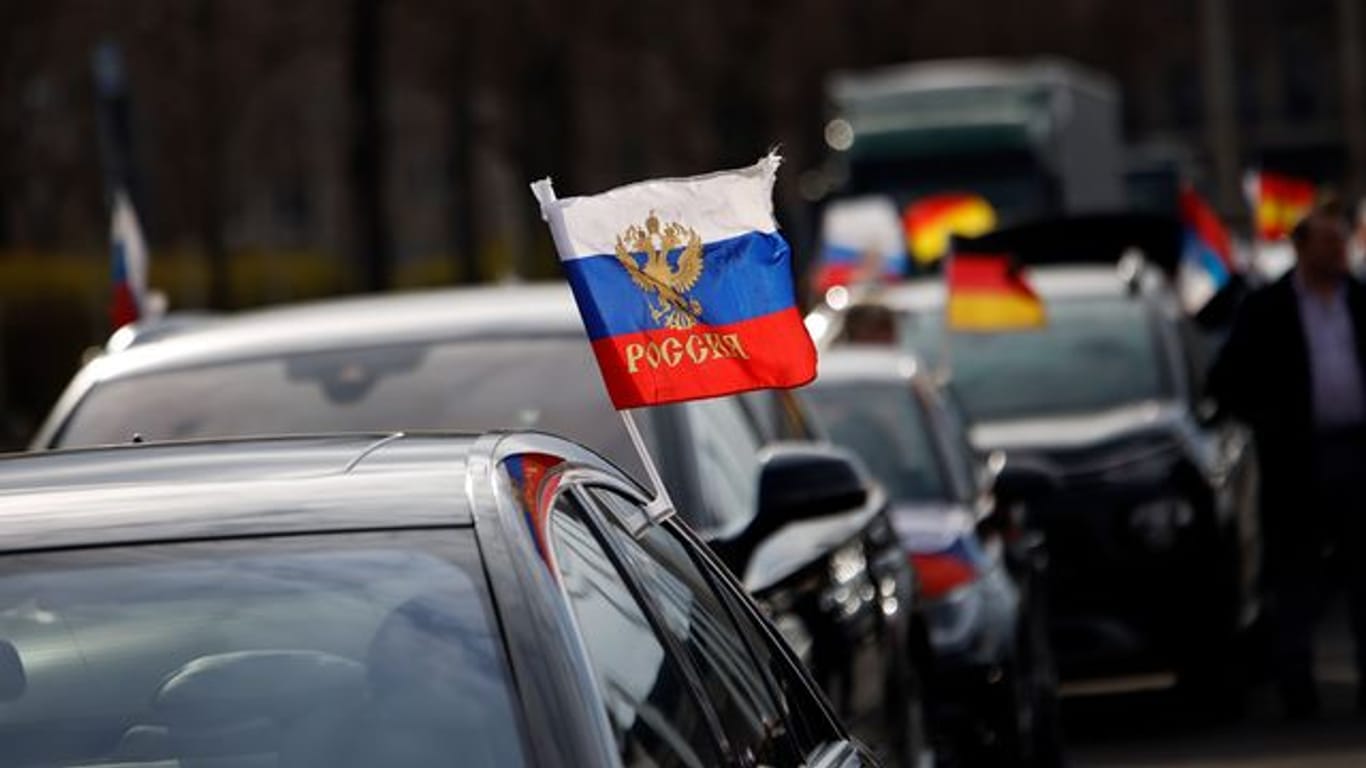 Eine Flagge mit den russischen Nationalfarben und dem russischen Staatswappen wehen an einem Auto (Archivbild): Nach dem prorussischen Autokorso am Wochenende üben Innenpolitiker Kritik.