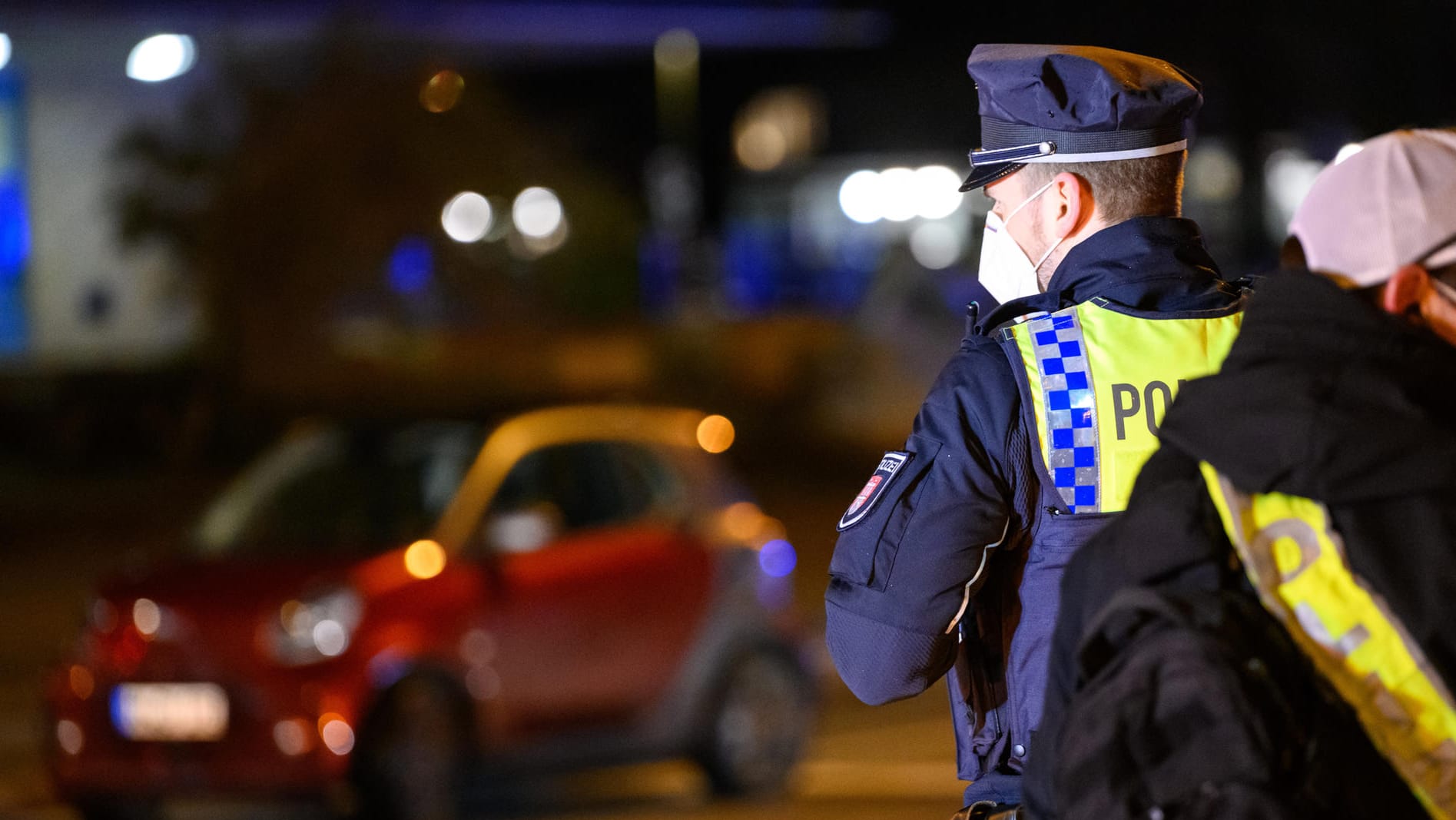 Zwei Polizisten stehen in der Nähe des beschädigten Unfallautos: Der Polizist musste ins Krankenhaus.