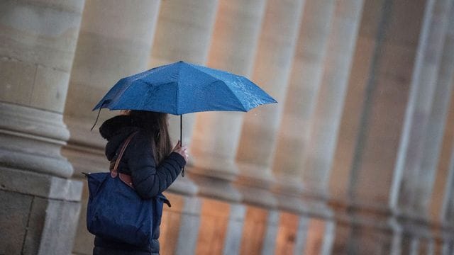 Eine Passantin geht bei Regen durch die Stadt