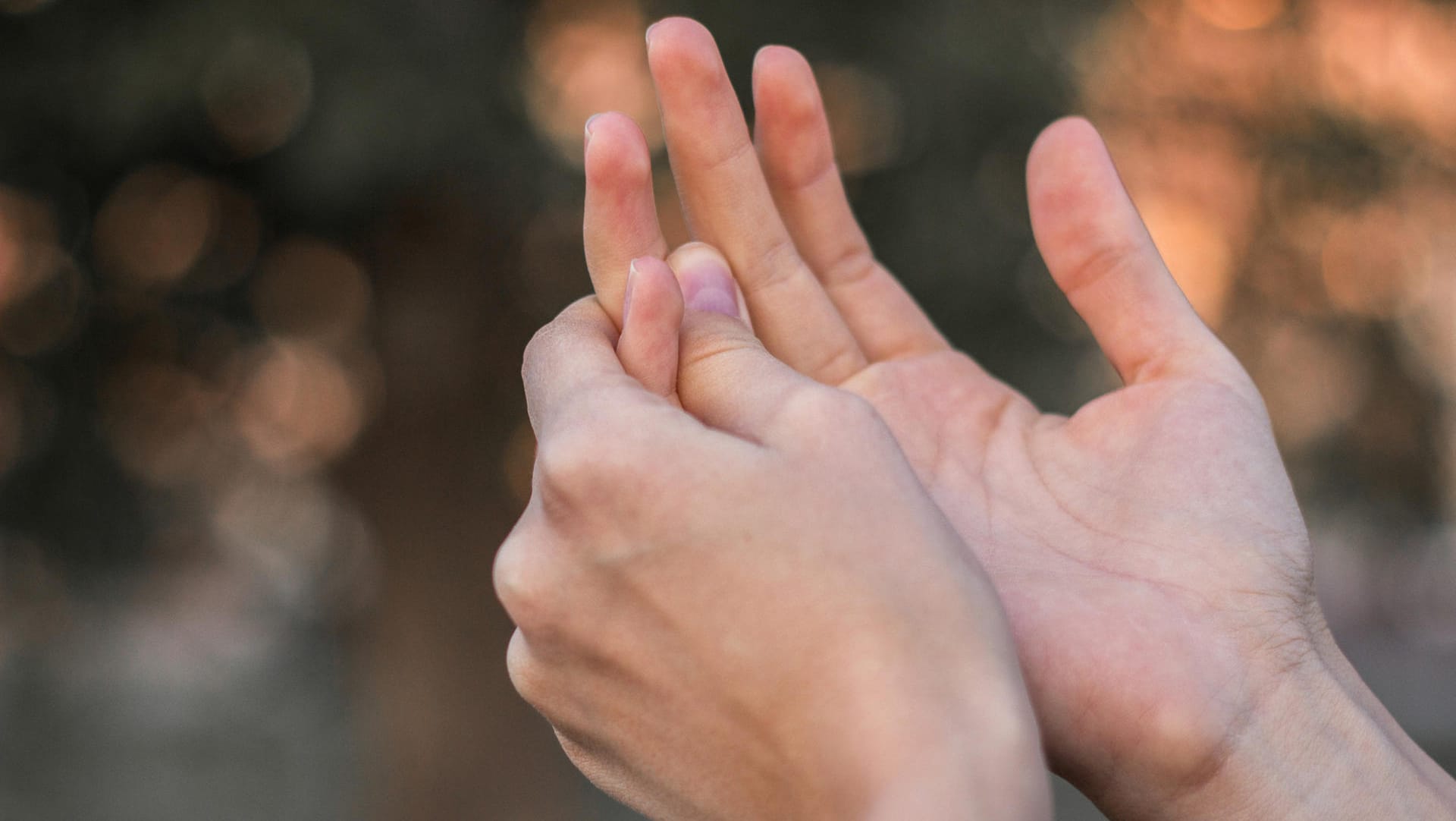 Frau fasst sich an Finger: Eine Arthrose in den Finger wird oft durch eine genetische Veranlagung hervorgerufen.