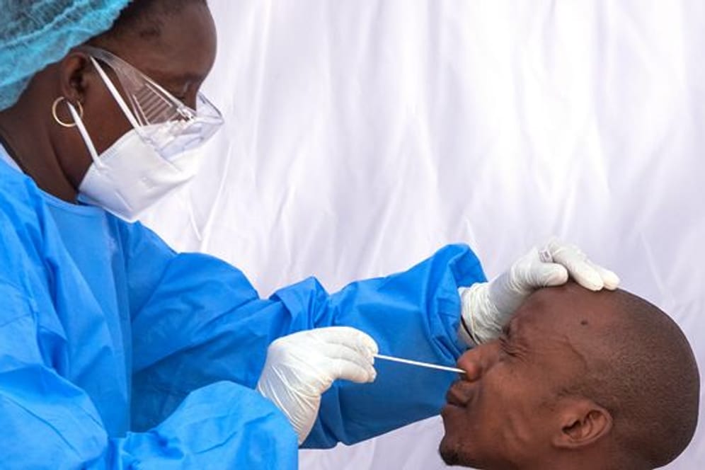 Eine Mitarbeiterin des Gesundheitswesen nimmt zur Bekämpfung der Corona-Pandemie einen Nasen-Abstrich eines Mannes.
