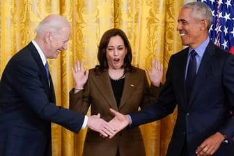 US-Vizepräsidentin Kamala Harris (M) reagiert auf den Handschlag von Präsident Joe Biden (l) und seinem Vorgänger Barack Obama.